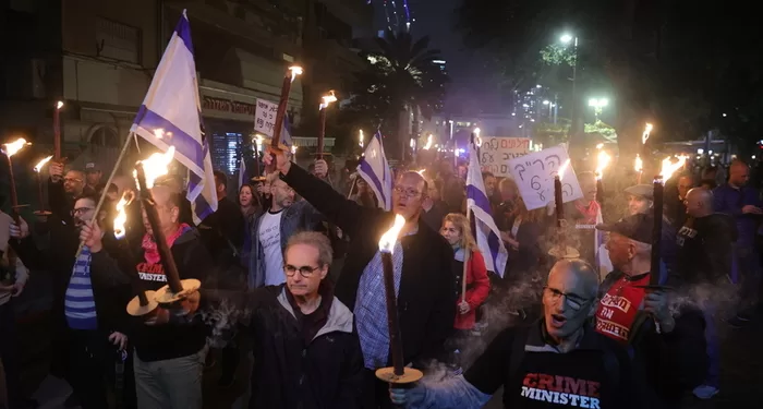 epa10394632 Israeli protesters light torches as they take part in a protest march against the new government in Tel Aviv, Israel, 07 January 2023. A statement made by the new minister of justice Yariv Levin declaring his intention to reform and weaken the power of the Israeli Supreme Court led people out to demonstrate against the new Netanyahu government  EPA/ABIR SULTAN