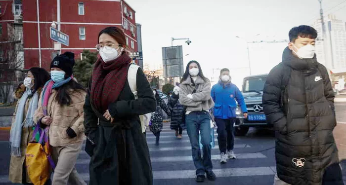 epa10386829 People wearing face masks walk in the business district of Beijing, China, 03 January 2023. Scientists have warned China that the country will face multiple waves of COVID-19 infections as the Omicron variant mutates to spread faster and evade immunity. According to virologist Shan-Lu Liu from Ohio State University in the USA, reinfection rates would rise as vaccine protection dwindled. People from Beijing, Shanghai and Wuhan have returned to work as restrictions have been lifted and as China attempts to recover its economy.  EPA/MARK R. CRISTINO