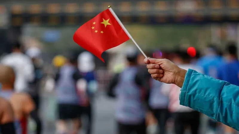 epa10289411 A spectator waves the Chinese flag as runners compete during the Beijing Marathon in Beijing, China, 06 November 2022. The Beijing Marathon resumed after a two year hiatus following the COVID-19 pandemic. Participants were limited and were required to follow strict COVID-19 protocols before being able to join the race. EPA/MARK R. CRISTINO